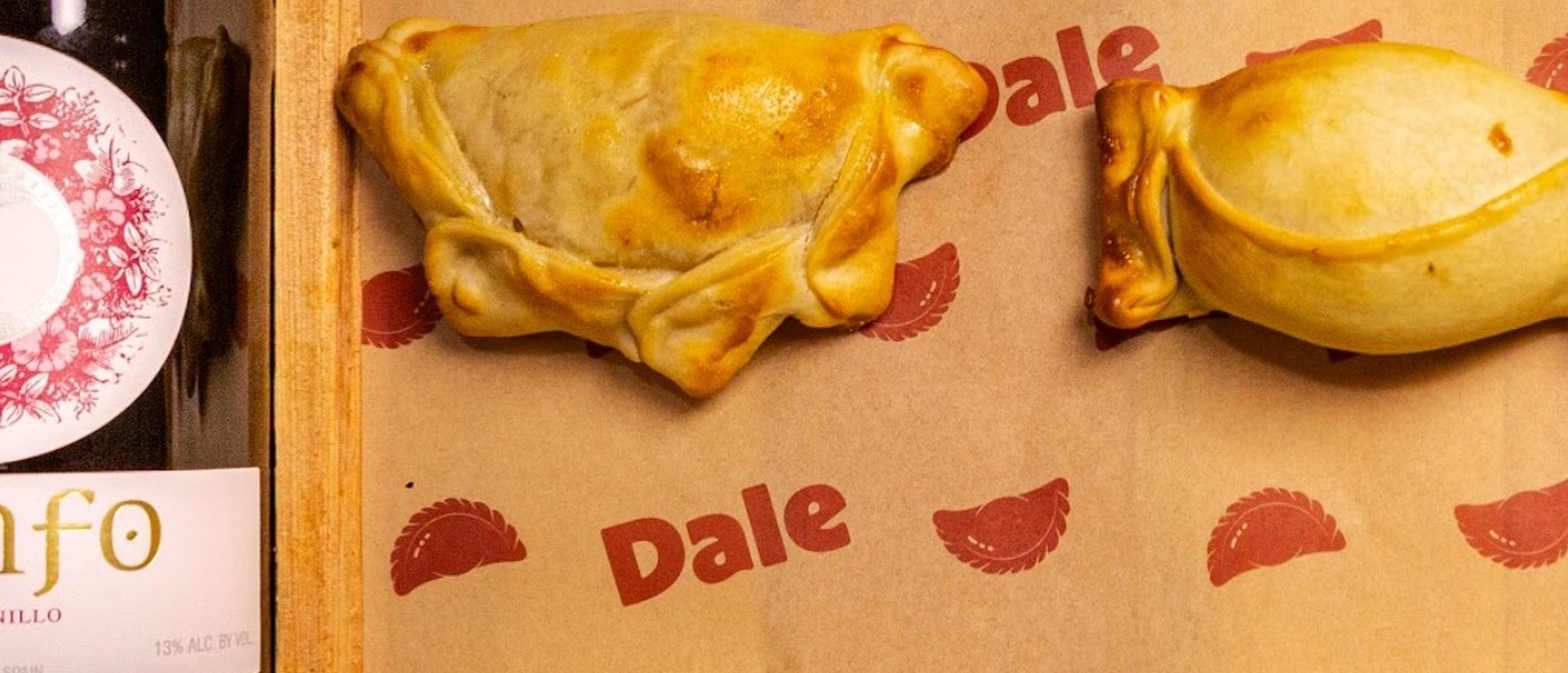 Bandeja de empanadas da Dale ao lado de uma garrafa de vinho